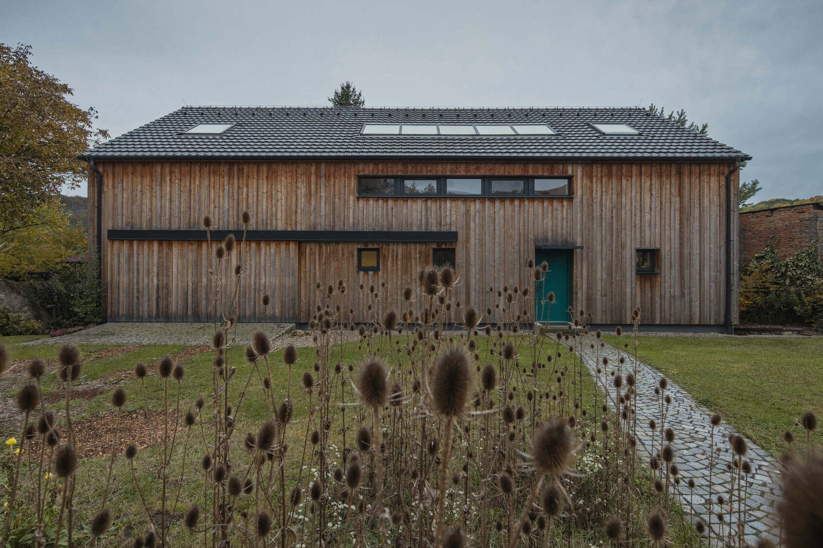 Družinska hiša kot tiho sozvočje krajine, lesa in svetlobe